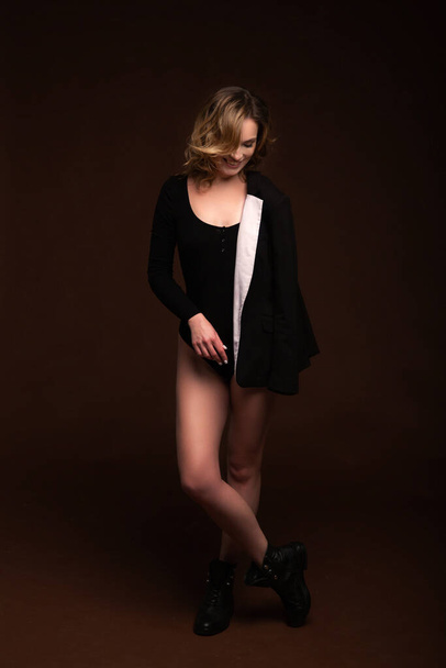 Blondi nainen musta body suit takki poseeraa ruskea tausta. - Valokuva, kuva