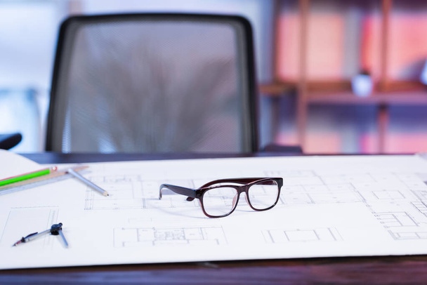 selective focus of eyeglasses and blueprint on desk in architectural agency, blurred background - Photo, Image