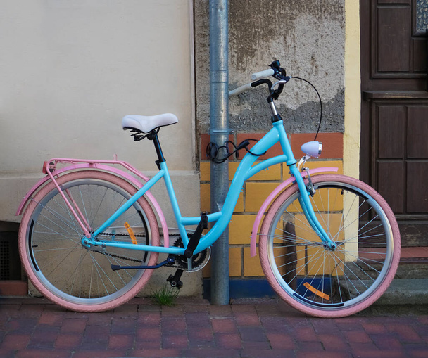 new vintage bicycle  and decorative tiled wall in Wismar, Germany. pink and blue bike standing near wooden door. - Fotoğraf, Görsel