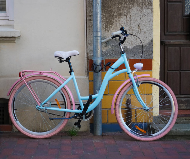 new vintage bicycle  and decorative tiled wall in Wismar, Germany. pink and blue bike standing near wooden door. - Photo, Image