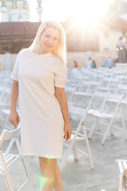 viehättävä nainen pukeutunut valkoinen mekko kesällä ulkona teatteri tuoli yksin, kevät katu tyyli muoti trendi, sosiaalinen etäisyys - Valokuva, kuva