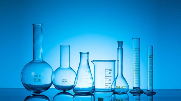 A variety of glass flasks and lab equipment on a blue background  - Photo, image