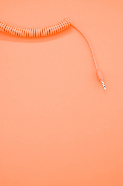 A vertical shot of a headphone cable on a pastel orange background for a copy space - Photo, image