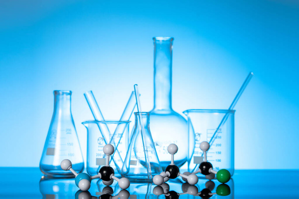 Una varietà di fiaschette di vetro e attrezzature da laboratorio su sfondo blu  - Foto, immagini