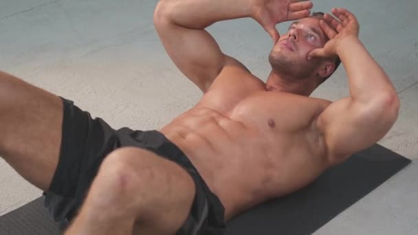 Спортивний і без сорочки чоловік робить вправи для своєї преси на килимі в спортзалі
 - Кадри, відео