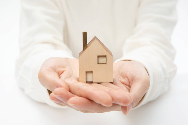 A closeup shot of hands holding a small wooden house-real estate concept - Photo, Image