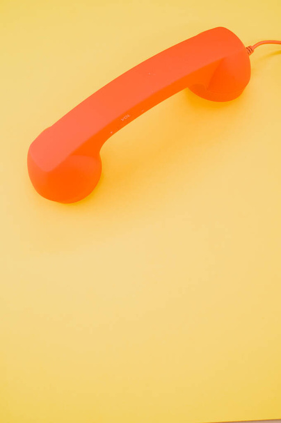 A vertical shot of a classic orange handset on pastel yellow background for a copy space - Foto, Bild