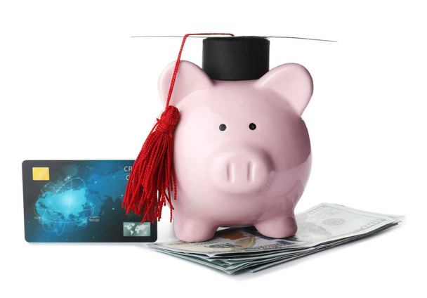 Prasečí banka s maturitní čepicí, kreditní kartou a dolarovými bankovkami na bílém pozadí - Fotografie, Obrázek