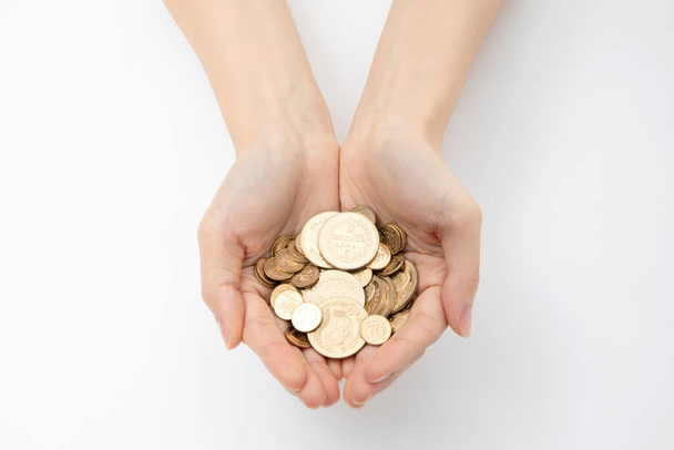 A closeup shot of hands holding various coins on a white background - Foto, afbeelding