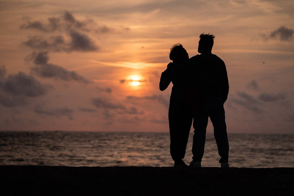 A beautiful shot of the siluette of a loving couple admiring the ocean in Guernsey at sunset - Fotografie, Obrázek