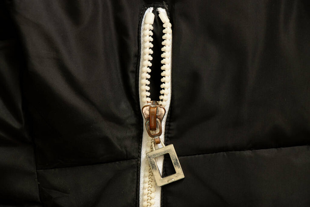 weißer Reißverschluss auf schwarzem Hintergrund in Nahaufnahme, Reißverschluss an Jacke in Nahaufnahme - Foto, Bild