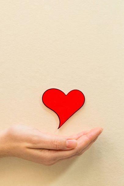 A female hand holding a red heart - spreading love everywhere - Φωτογραφία, εικόνα