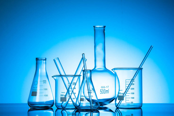 Różne kolby szklane i sprzęt laboratoryjny na niebieskim tle - Zdjęcie, obraz