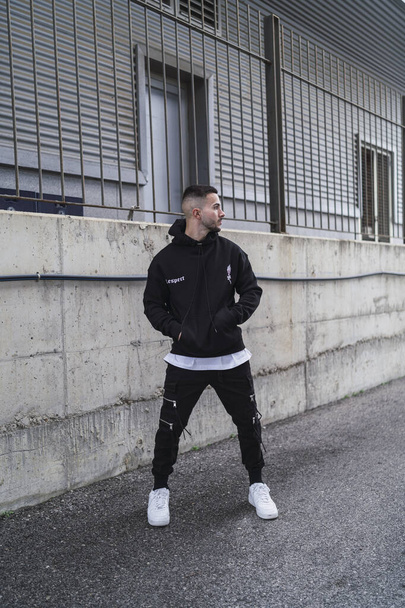 A vertical shot of a young trendy male posing in a black streetwear outfit - Foto, immagini
