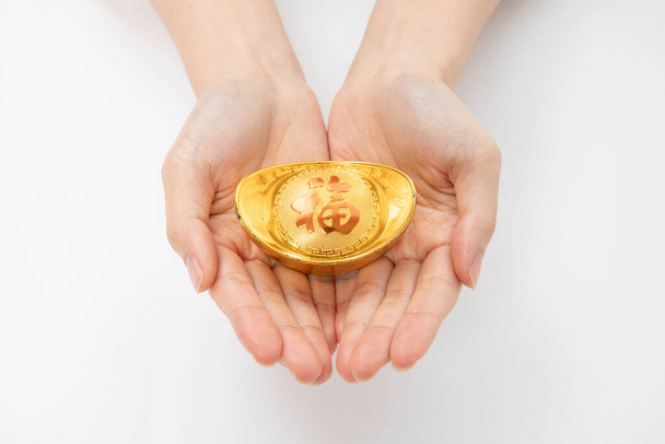 A closeup shot of hands holding a gold ingot - Φωτογραφία, εικόνα