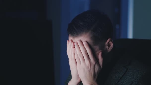 Fatigué jeune homme d'affaires travaille à un ordinateur portable tard dans la nuit, souffre de fatigue et de burnout émotionnel. surveiller la réflexion de la lumière sur son visage - Séquence, vidéo