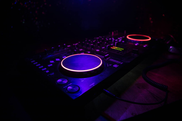 Koncepcja muzyki klubowej. DJ konsola DJ mieszanie biurko w ciemności z kolorowym świetle. Mixer sprzęt rozrywka DJ stacji. Skupienie selektywne - Zdjęcie, obraz