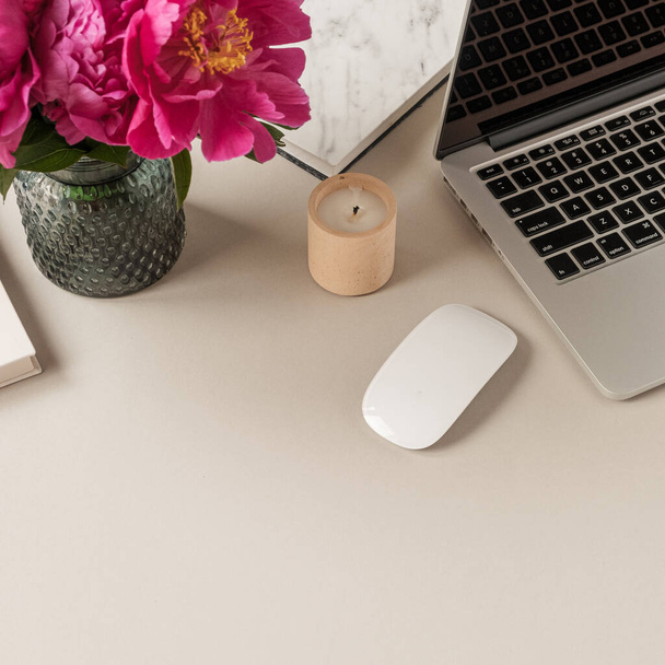 ノートパソコン、中立テーブルの背景に美しいピンクの牡丹チューリップの花花束。最小限のホームオフィスデスクワークスペース. - 写真・画像