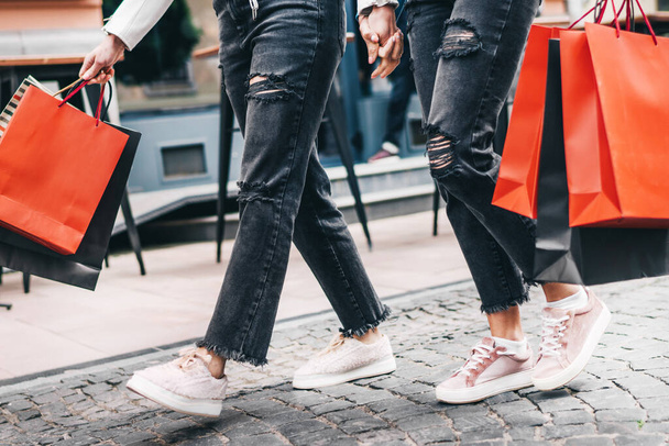 Photo of female legs stepping forward in shopping hands. - Фото, изображение