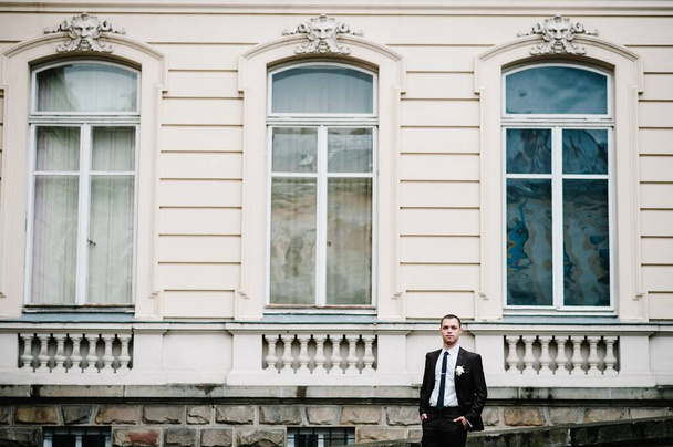Handsome attractive portrait groom in wedding suit stand near old building outside, vintage palace outdoor. - Foto, Imagem