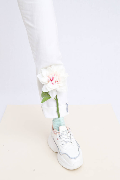 Details of trendy casual spring summer fresh outfit. Girl in studio wearing white jeans and stylish  sneakers. Everyday look. No face. Minimalist pastel colours aesthetic. - Valokuva, kuva