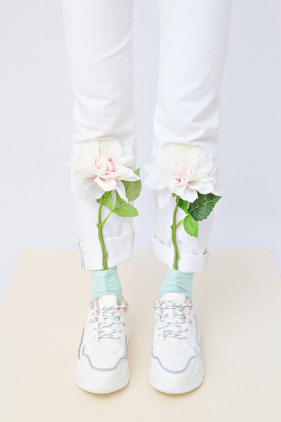 Details of trendy casual spring summer fresh outfit. Girl in studio wearing white jeans and stylish  sneakers. Everyday look. No face. Minimalist pastel colours  concept - Valokuva, kuva
