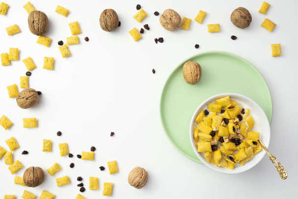 cornflakes, raisins and muesli in a plate near walnuts on a table on a white background - Photo, Image