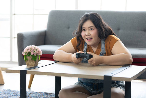 satisfaire chubby femme jouer à des jeux vidéo à la maison - Photo, image