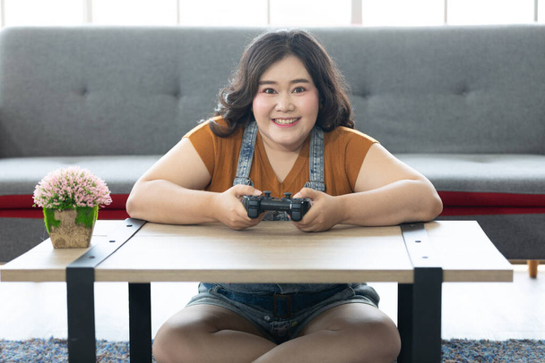 satisfaire chubby femme jouer à des jeux vidéo à la maison - Photo, image