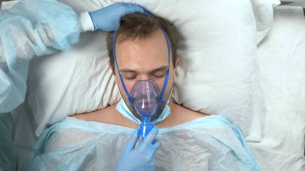 portrait of a man in an oxygen mask who lies on a bed in a hospital - Фото, зображення