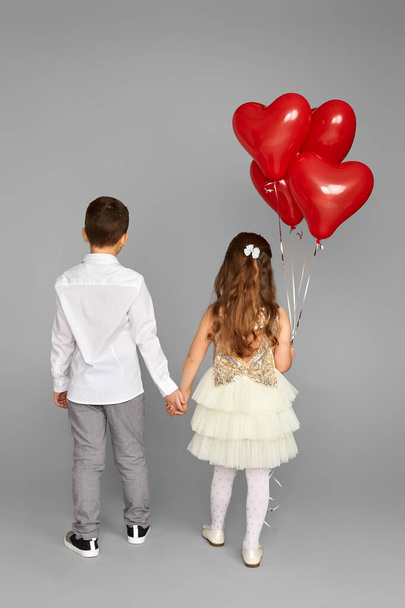 couple of little girl and boy with red heart balloons - Fotó, kép
