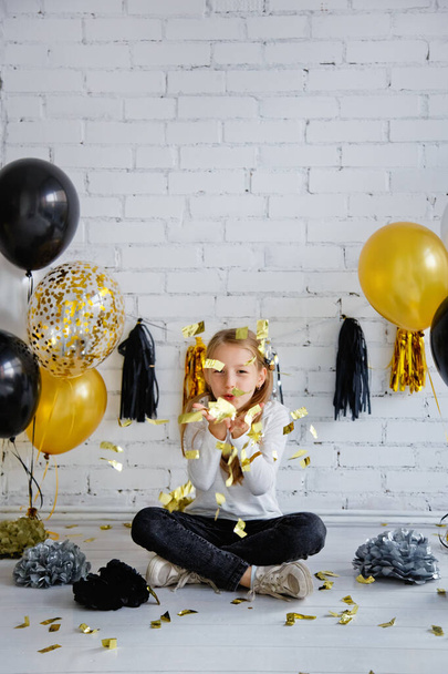 День народження дівчинки прикрашена чорною і золотою кулею. Дме на confetti
. - Фото, зображення