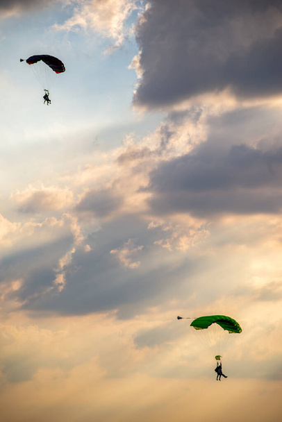 parachutists descending in the cloudy sky - Фото, изображение