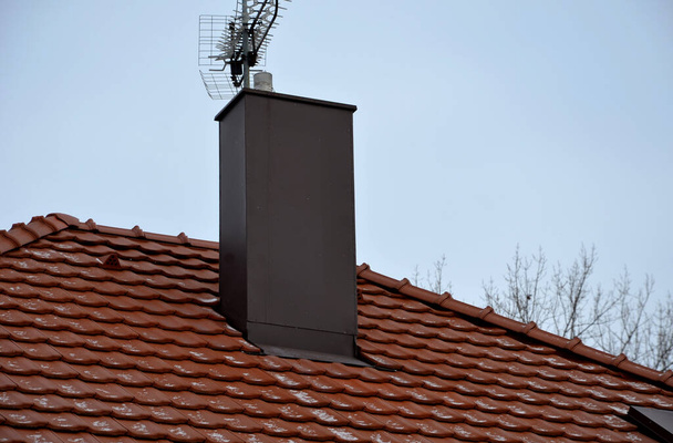 beplating van de schoorsteen op het dak van verbrande tegels. schoorsteenbescherming tegen regen, vorst en sneeuw met een bruine plaat. De tinsmid kan het in detail inpakken en er is geen gevaar dat het plaatmetaal - Foto, afbeelding