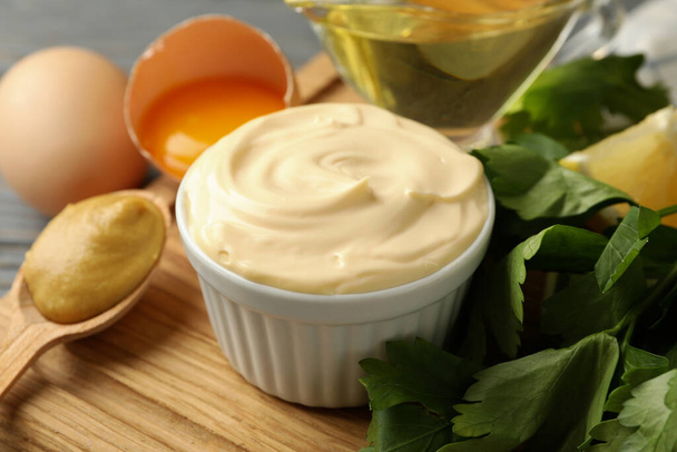 Board with bowl of mayonnaise and ingredients for cooking on wooden background - Photo, Image