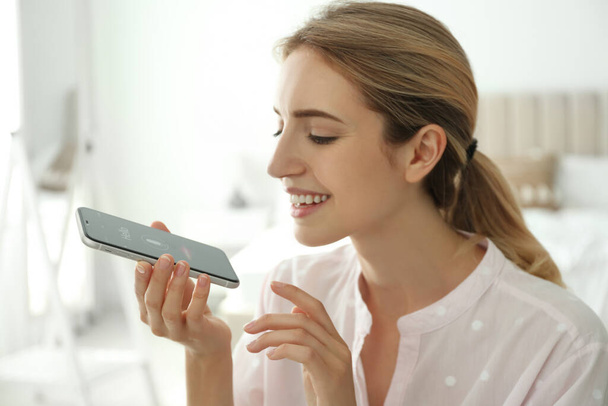 Young woman using voice search on smartphone indoors - Photo, image