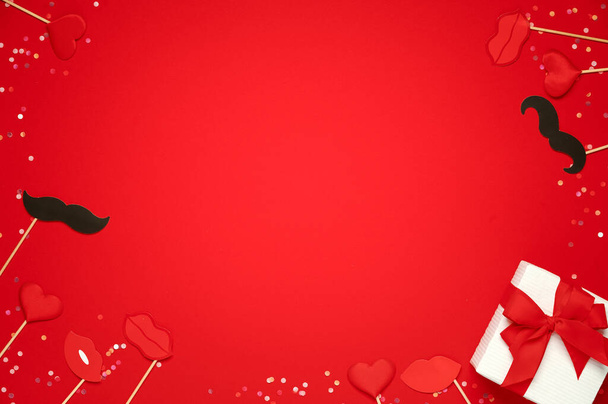 Coffret cadeau et doux cœurs lèvres et moustache de papier sur fond rouge. Modèle de Saint-Valentin - Photo, image