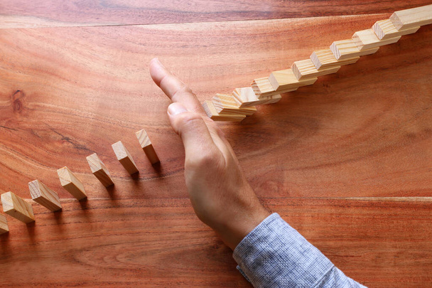 image of male hand stopping the domino effect. executive and risk control concept - Photo, image