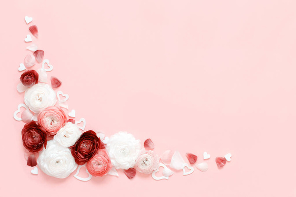 Kulma runko ranunculus kukkia, terälehtiä ja sydämiä vaalean vaaleanpunainen tausta ylhäältä näkymä. Kevään konsepti - Valokuva, kuva
