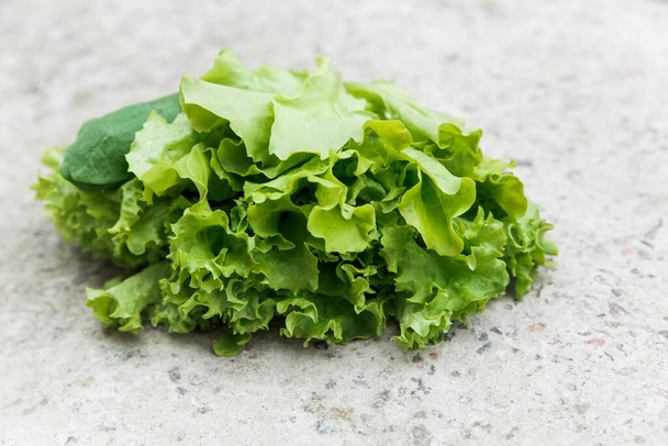 świeża zielona sałata z ogrodowego łóżka na kamiennym tle. żywność ekologiczna i koncepcja zdrowego stylu życia - Zdjęcie, obraz