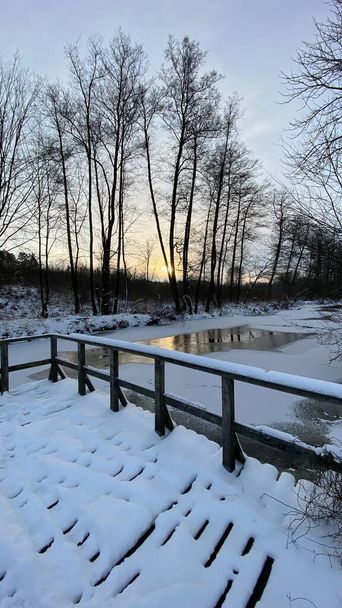 Zimowy krajobraz rzeka  zamarznita pola i lasy w okolicach Wlodawy pokrytej duo niegu niego w zlotejj godzinie - Foto, Bild
