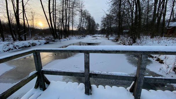 Zimowy krajobraz rzeka  zamarznita pola i lasy w okolicach Wlodawy pokrytej duo niegu niego w zlotejj godzinie - Foto, afbeelding