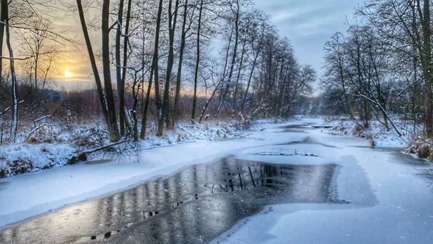 Zimowy krajobraz rzeka czuciowo  zamarznita pola i lasy w okolicach Wodawy pokrytej duo niego w zotej godzinie - Foto, afbeelding
