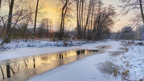 Zimowy krajobraz rzeka czuciowo  zamarznita pola i lasy w okolicach Wodawy pokrytej duo niego w zotej godzinie - Photo, image