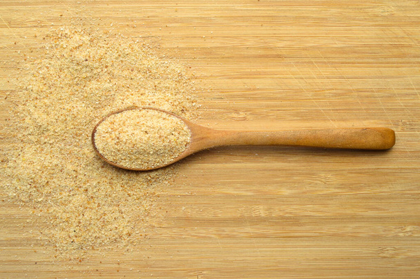 Świeże i smaczne okruszki chleba mąka galeta w drewnianej łyżeczce na brązowej desce do cięcia bambusa - Zdjęcie, obraz