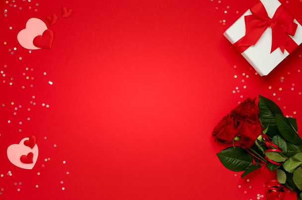 Happy valentine day. Bunch of red roses with gift box and many soft hearts over red background - Photo, Image