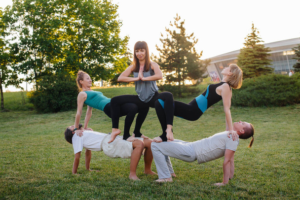 A group of people do yoga in the Park at sunset. Healthy lifestyle, meditation and Wellness - Foto, imagen