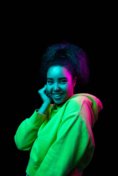 African-american womans portrait isolated on dark studio background in multicolored neon light - Foto, imagen