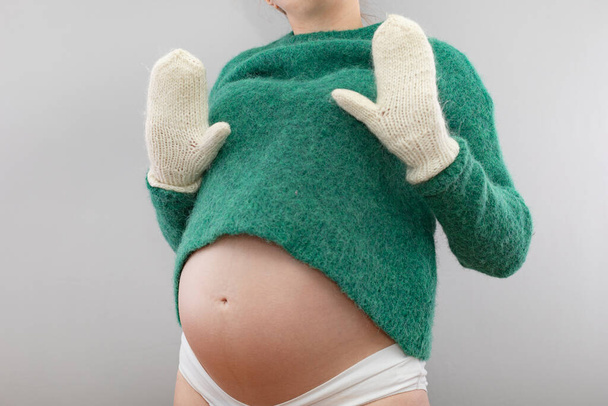 Έγκυος γυναίκα με μάλλινο πουλόβερ και ζεστά γάντια - Φωτογραφία, εικόνα