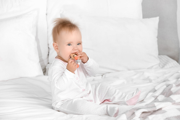 Cute little baby with teething toy sitting on bed - Photo, Image
